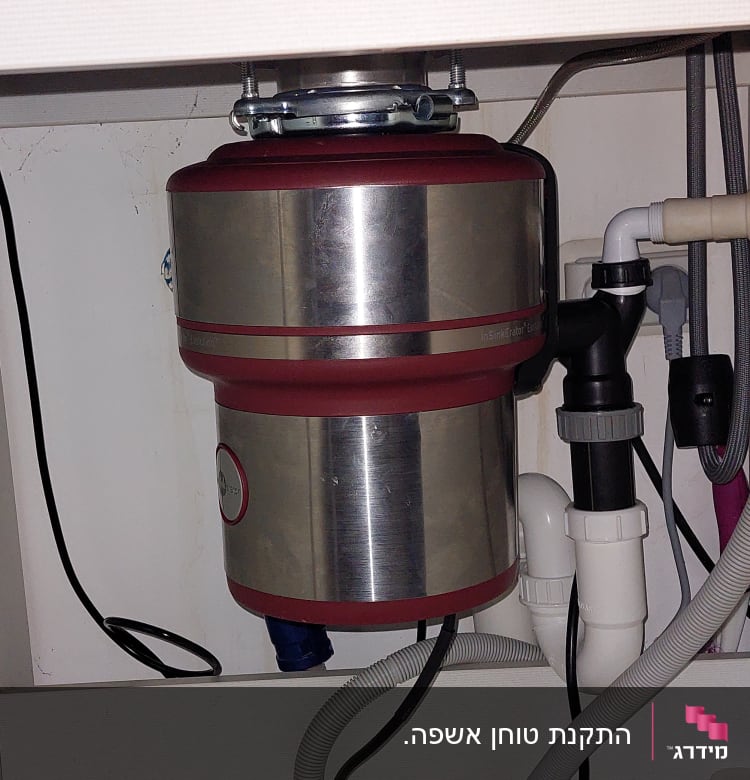 מתקן טוחן אשפה מתחת לכיור עם צינורות חיבור